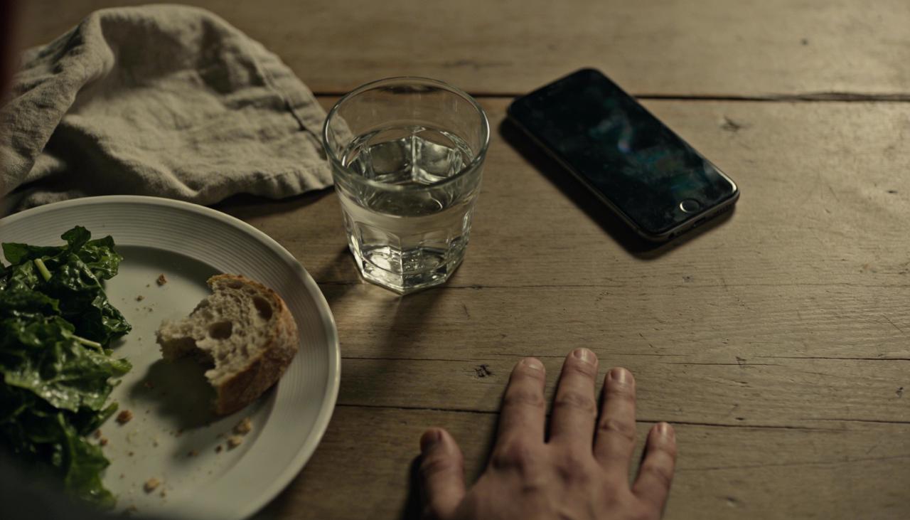 A half-eaten salad, a glass of water, and a phone on a wooden table — the quiet weight of food decisions